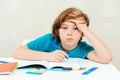 Tired schoolboy sitting at table. Boy doing homework. Learning difficulties, education concept Royalty Free Stock Photo