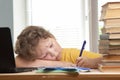 Tired schoolboy sitting at table doing homework Royalty Free Stock Photo