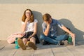 Tired schoolchildren teenagers sitting outside at gray wall with books, backpacks Royalty Free Stock Photo