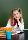 Tired schoolgirl with pile books near empty green chalkboard Royalty Free Stock Photo