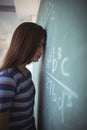 Tired schoolgirl standing with closed eyes near chalkboard in classroom Royalty Free Stock Photo