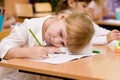 Tired schoolgirl writes in a notebook during lesson