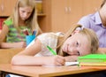 Tired schoolgirl writes in notebook during lesson