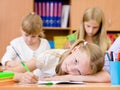 Tired schoolgirl writes in a notebook during lesson Royalty Free Stock Photo