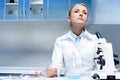 Tired scientist in white coat sitting at workplace in laboratory