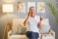 Tired senior with glasses. Sore eyes from infection. mature old man wearing white T-shirt rubbing and wiping eyes sitting on sofa Royalty Free Stock Photo