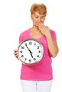 Tired senior woman holding clock and yawning Royalty Free Stock Photo