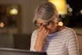 Tired senior woman with laptop at home at night Royalty Free Stock Photo