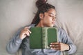 Tired, sleeping student with book on bed after studying, reading or learning knowledge at home. Burnout gen z or young Royalty Free Stock Photo