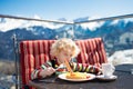 Child eating apres ski lunch. Winter snow fun for kids.