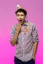 Tired sleepy man yawning at birthday party over purple background. Royalty Free Stock Photo