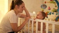 Tired sleepy mother rocking crib of her baby crying and refusing to sleep at night. Concept of parenting, parent fatigue Royalty Free Stock Photo