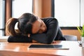 Tired sleepy young Asian female worker or college student sleeping on the desk Royalty Free Stock Photo