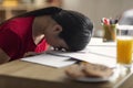 Tired sleepy young chinese lady student lies and sleeps on table with notebooks in room interior, close up Royalty Free Stock Photo