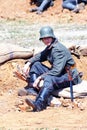 A tired soldier-reenactor sits on the ground.