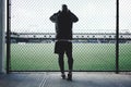 Tired sportsman leaned and looking throurh the rabitz fence on football field