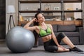 Tired sportswoman sitting near fitness ball at home and Royalty Free Stock Photo