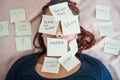 Tired, sticky note and sleeping woman in overworked, schedule or overwhelmed with work and tasks on bed. Female worker