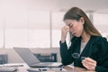 Tired and stressed asian business woman closed eyes massaging nose and sitting at desk in front of laptop at office background