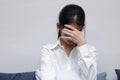 Tired stressed young Asian woman covering face with hands in living room.