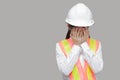 Tired stressed young Asian worker covering face with hands on gray isolated background