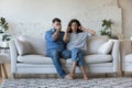 Tired stressed young couple arguing at home, sitting on sofa