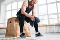 Perspiring fit sportsman resting with towel after hard crossfit workout in light hall