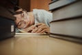 Tired student girl with glasses lying on books in library Royalty Free Stock Photo