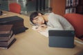 Tired student girl with glasses lying on books in library Royalty Free Stock Photo