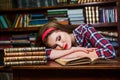 Tired student girl sleeping on the books in the library Royalty Free Stock Photo