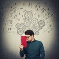 Tired student guy, holds a book, looks down with pessimistic emotion. Man pondering, focuses his mind, thinking of solutions to