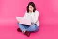 Tired student with laptop sits on floor with closed eyes. Brunette girl keeps hand near temple because sufers from headache. Royalty Free Stock Photo