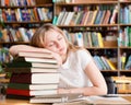 The tired student sleeps in library on pile books Royalty Free Stock Photo