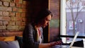 Female student typing coursework by laptop at cafe.