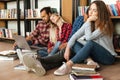 Tired students sitting in library on floor using laptop computer Royalty Free Stock Photo