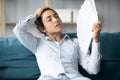 Tired indian woman using fan sit on couch at home