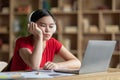 Tired teen asian lady in headphones falls asleep at table with laptop in room interior Royalty Free Stock Photo