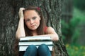 Tired teen girl with books in the park.