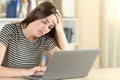 Tired teen using a laptop on a desk at home