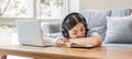 Tired teenage asian female student fell asleep at her desk, resting her head on her hand, during a lecture in home Royalty Free Stock Photo