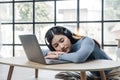Tired teenage asian female student fell asleep at her desk, resting her head on her hand, during a lecture in home Royalty Free Stock Photo