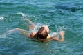 Tired teenage girl swims on her back in the sea