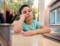 Schoolboy looks dejectedly at laptop screen, having difficulty perceiving information during online lesson with teacher