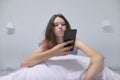 Tired teenager girl sitting at home in bed looking at mobile phone Royalty Free Stock Photo