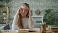 Tired teenager touching head feeling headache doing homework in apartment