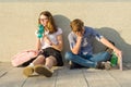 Tired teenagers schoolchildren sit near the gray wall of the school Royalty Free Stock Photo