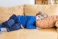 Tired toddler boy laying on couch at home