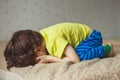 Tired toddler boy lying on the bed with his face down. Crying little kid