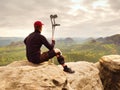 Tired tourist with medicine crutch and broken leg fixed in immobilizer resting on mountain summit