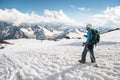 The tired traveler descends from the snowy top against the background of snow-capped mountains